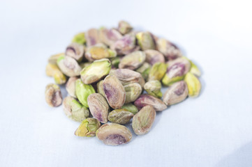 A heap of pistachio nuts on a white background on a sunny day.