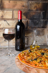 Pizza with wine and oil on a firebricks background