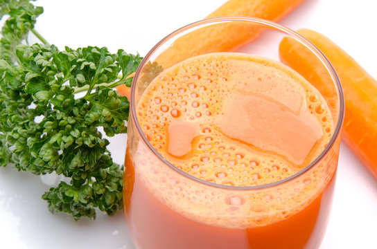 Composition with a glass of carrot juice, fresh carrots and pars