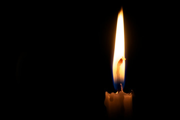 Closeup of burning candle isolated on black background.