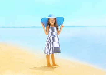 Fashion little girl in a striped dress and hat relaxing