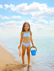 Happy little girl playing on the beach near sea, summer