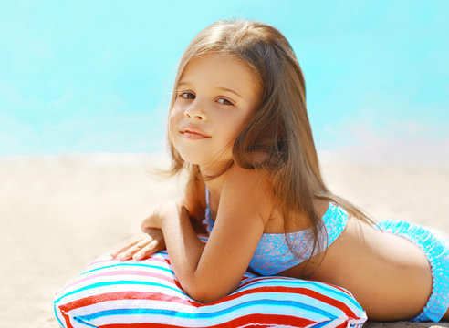 Summer vacation, little girl resting on the beach near sea