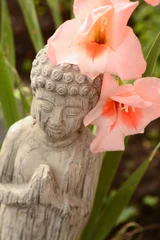 Tapeten Boeddha in  bamboe tuin met bloemen © trinetuzun