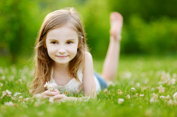 Naklejka na ściany i meble Cute little girl laying in the grass