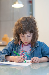 Little girl sitting at a table drawing and coloring in her book