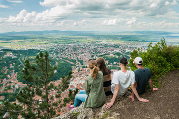 Group of friends sitting on the edge of cliff looking at city