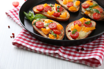 Tasty bruschetta with tomatoes in pan, on table