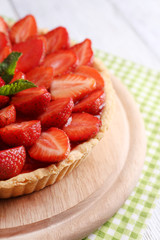 Strawberry tart on wooden tray, on color wooden background