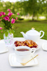 Coffee table with teacups and tasty pie in garden