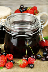 Tasty jam with berries in glass jars on wooden table