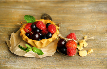 Tasty tartlets with berries on wooden table