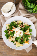 Green salad with apples, walnuts and cheese on wooden