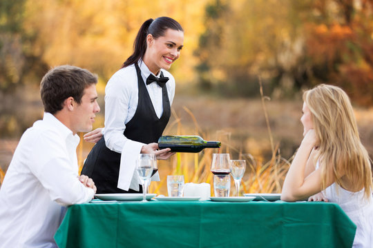 Waitress Pouring Wine For Romantic Couple