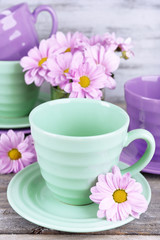 Cups and saucers with flowers on wooden background