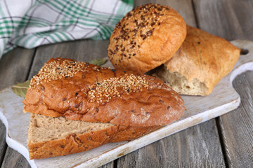 Fresh baked bread on cutting board, on wooden background