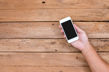 Man hand holding smart phone on wood background