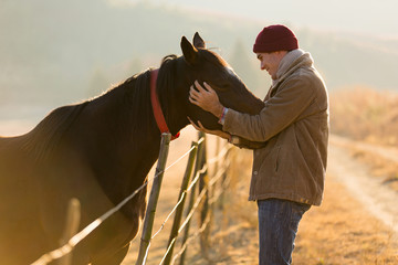 young man touching his horse - obrazy, fototapety, plakaty
