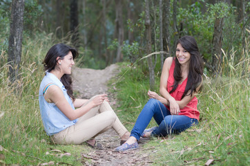 Two beautiful girls sitting in a forest