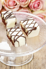 Chocolate and marzipan cakes on glass cake stand.