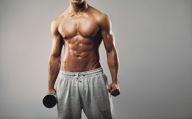 Shirtless young muscular man with dumbbell