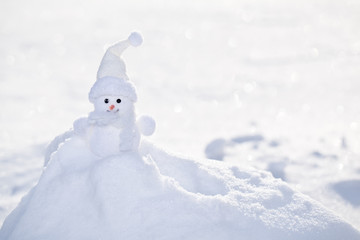Little white snowman near snowbank.
