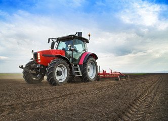 Naklejka premium Farmer in tractor preparing land for sowing