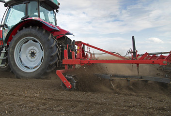 Close-up of agriculture red tractor cultivating field
