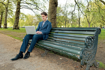 Businessman with a laptop sitting in a park