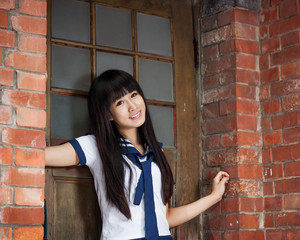 Asian schoolgirl outside brick building