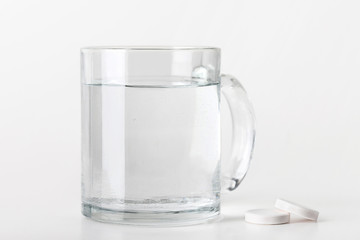 water cup isolated near two tablet on white background