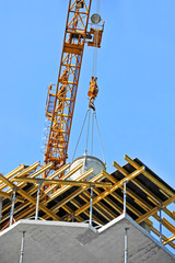 Crane lifting concrete mixer container against blue sky