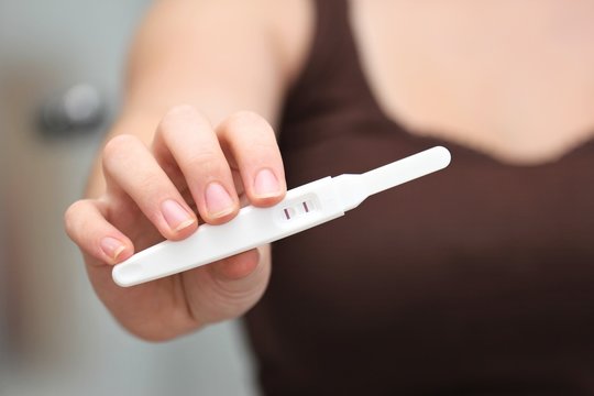 positiver Schwangerschaftstest gezeigt von junger Frau