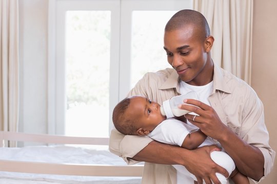 Happy Father Feeding His Baby Boy A Bottle