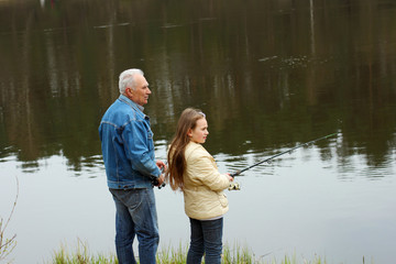 Grandfather and granddaughter are fishing
