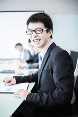 Businessman smiling at the camera while his team is working in t