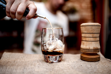 bartender pouring alcoholic liquor in small glass on the counter