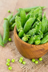 fresh pea pods in a wooden bowl