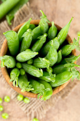 fresh pea pods in a wooden bowl