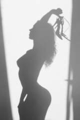 Beautiful naked woman silhouette, with sandals in hands