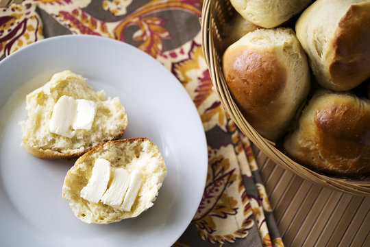 dinner rolls in basket and on white plate with butter