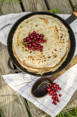 Pancakes with red currants. Near wooden spoon