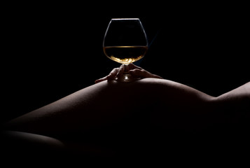 Beautiful, nude woman body silhouette and a glass of drink