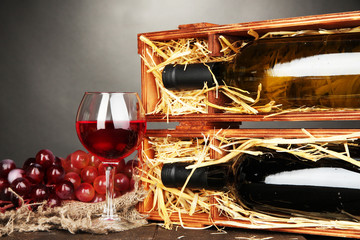 Fototapeta premium Wooden case with wine bottles, wineglass and grape