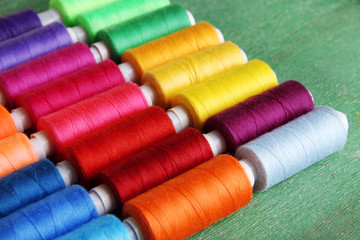 Multicolor sewing threads on wooden background