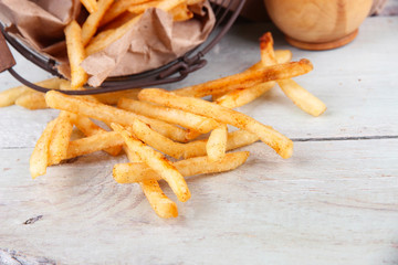 Tasty french fries in metal basket on wooden table