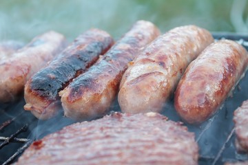 sausages and burgers cooking on barbecue