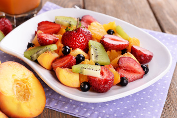 Fresh fruits salad on plate with juice on table close up