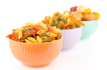 Assortment of colorful pasta in color bowls isolated on white