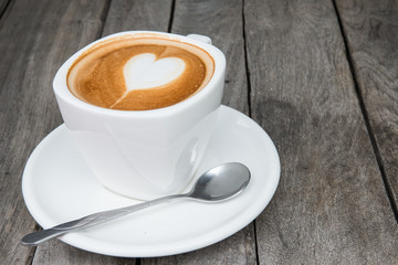 Cup of hot latte art coffee on wooden table